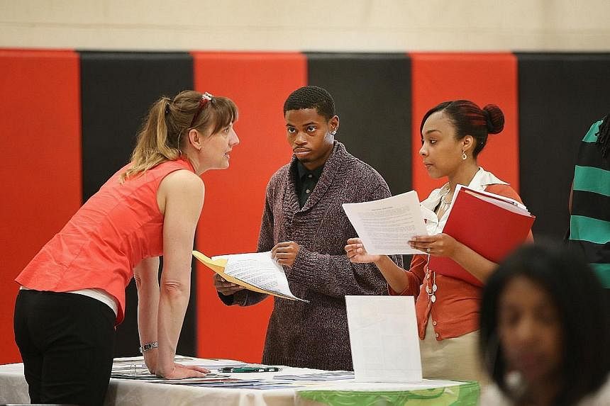 Ms Wendy Larsen (left) speaks to candidates at a job fair in Chicago, Illinois, on June 12, 2014. New US claims for unemployment insurance benefits fell last week, continuing to point to a downward trend in job losses, official data released on June 