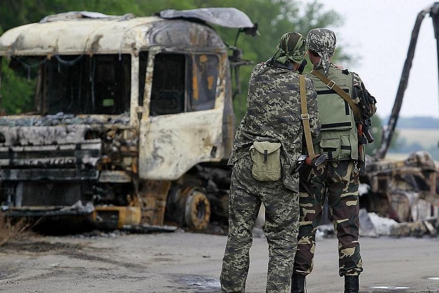 Pro-Russian separatists stand guard at a checkpoint near a burnt truck outside Luhansk on June 18, 2014.&nbsp;Ukrainian forces and pro-Russian separatists were locked in a fierce battle in the rebellious east of the country on Thursday, June 19, 2014