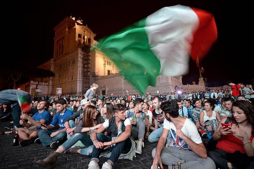 Italian fans celebrate their team's victory over England in the 2014 World Cup as they watch the match on a large screen in central Rome's Piazza Venezia on June 14, 2014. -- PHOTO: AFP