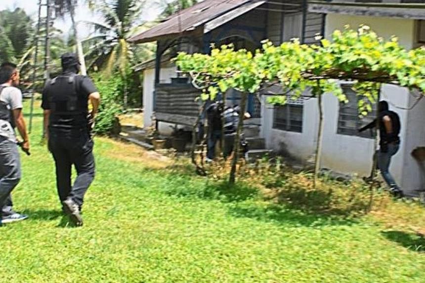 Members of Bukit Aman Counter Terrorism Division detaining a man after raiding his home in Kampung Kelebor in Kuala Kangsar. The 25-year-old man is believed to be the weapons handler for a militant group linked to the group waging wars in Syria and I