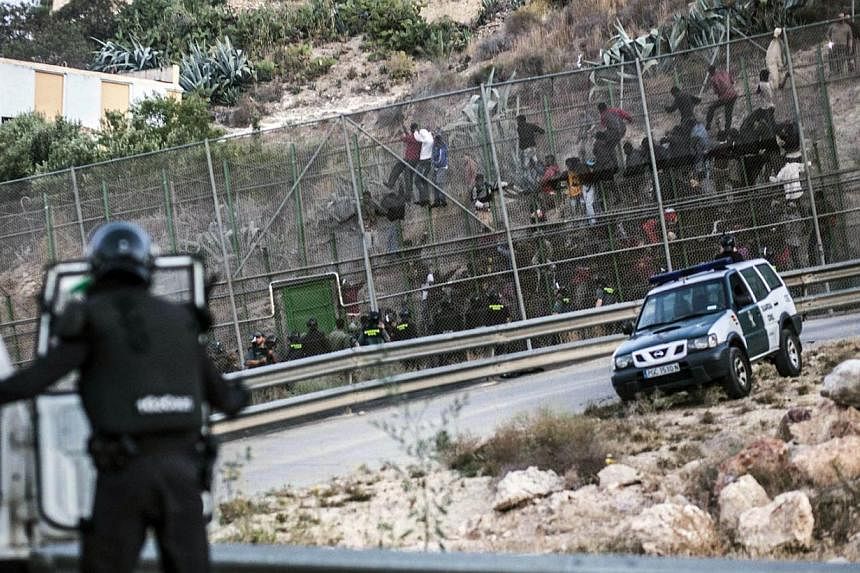 Would-be immigrants try to scale a boarder fence separating Morocco from the Spanish enclave of city of Melilla on June 18, 2014. Some 400 sub-Saharan migrants tried today unsuccessfully to enter Melilla with some 150 still stuck on the fence itself 