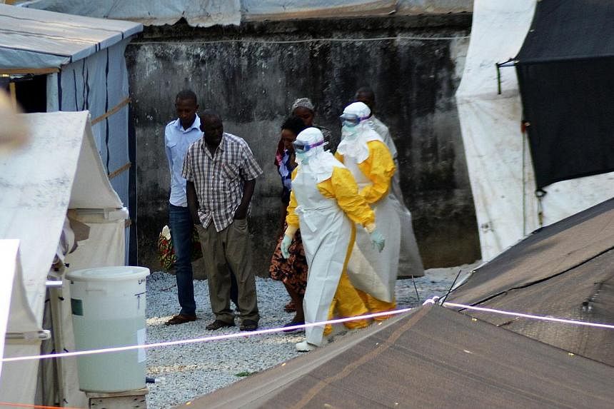 A file photo taken on April 14, 2014 shows health workers, wearing protective suits, walking in an isolation center for people infected with Ebola at Donka Hospital in Conakry. -- PHOTO: AFP