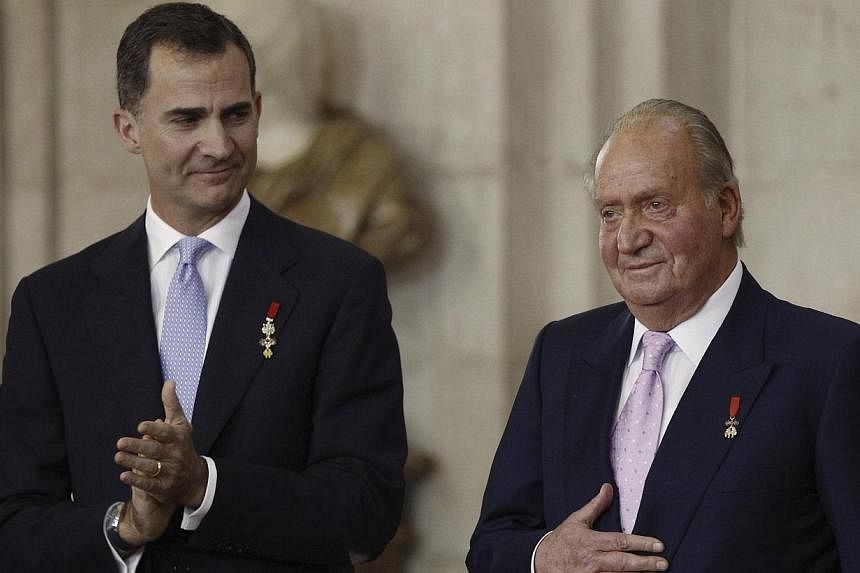 Spain's former king Juan Carlos (right) reacts next to his son Felipe during the signature ceremony of the act of abdication at the Royal Palace in Madrid on June 18, 2014. -- PHOTO: REUTERS