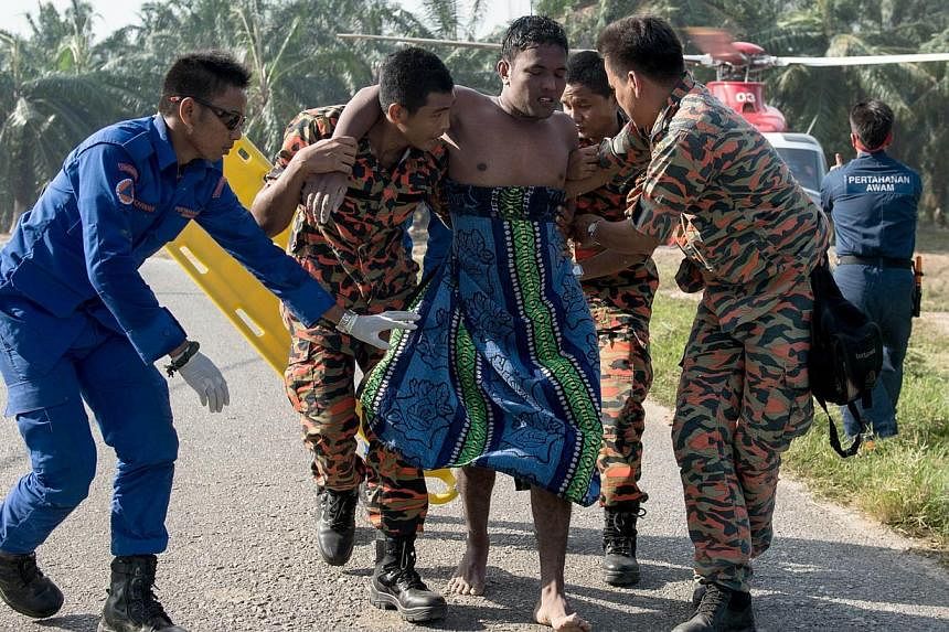 A Malaysian search and rescue team helps a rescued victim (centre) from a capsized boat in Kelanang Jetty, near Banting after an apparently overloaded boat carrying Indonesian illegal migrants sank in seas off western Malaysia on June 19, 2014. -- PH