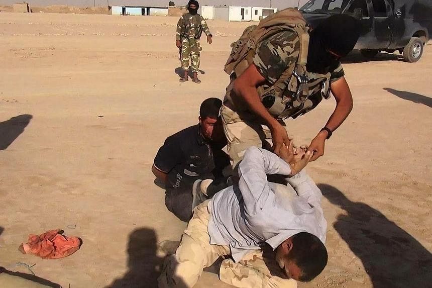 An image made available by the jihadist Twitter account Al-Baraka news on June 13, 2014 allegedly shows Islamic State of Iraq and the Levant (ISIL) militant restraining an unidentified man at an undisclosed location close to the Iraqi-Syrian border, 