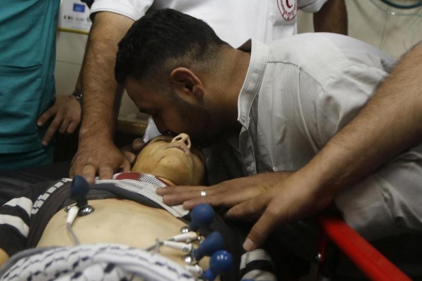 A man kissing the head of Palestinian teenager Mohammed Dudin, who medics said was killed by Israeli troops, at a hospital in the West Bank city of Hebron on Friday. PHOTO: REUTERS