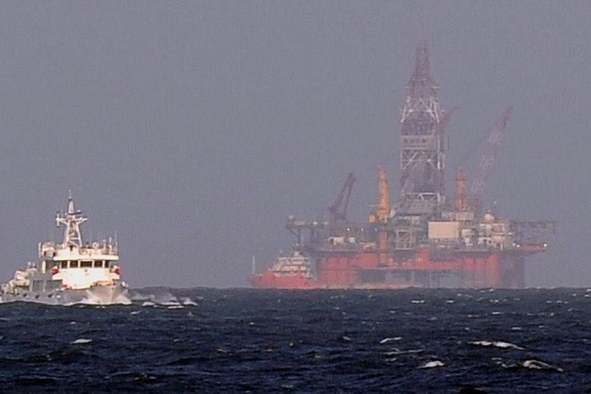 This file picture taken on May 14, 2014 from a Vietnamese coast guard ship shows a Chinese coast guard vessel (L) sailing near a Chinese oil rig in disputed waters in the South China Sea. -- PHOTO: AFP