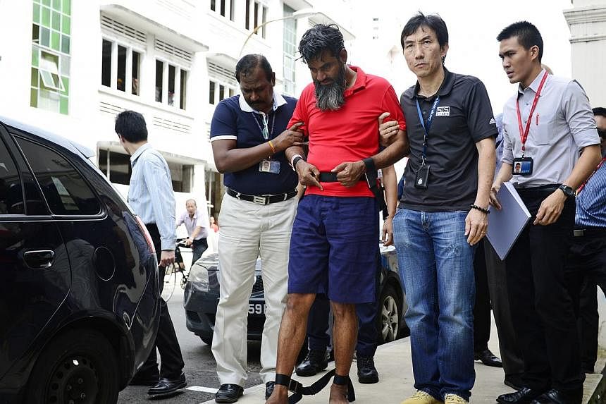Suitcase murder Pakistani suspect, Rasheed Muhammad, 43, uses his foot and fingers to point to what appears to be dried blood stains on the pavement along Syed Alwi Road. -- PHOTO: ST FILE