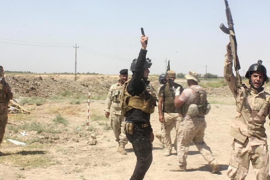 Members of the Iraqi security forces shout slogans as they carry weapons during clashes with Sunni militant group Islamic State of Iraq and the Levant (ISIL) in Muqdadiyah in Diyala province on June 19, 2014. -- PHOTO: REUTERS