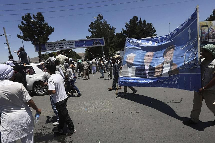 Afghan protesters carry a poster of presidential candidate Abdullah Abdullah during a demonstration in Kabul on June 21, 2014. Protesters gathered in the Afghan capital on Saturday in support of presidential candidate Abdullah Abdullah's accusation o