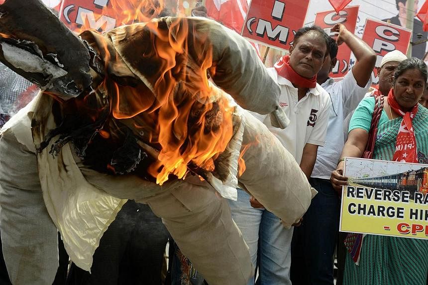 Indian activists of the Communist Party of India-Marxists (CPI-M) burning an effigy representing Prime Minister Narendra Modi during their protest against the price hike in railway fares, in Hyderabad on June 21, 2014. The government has increased th
