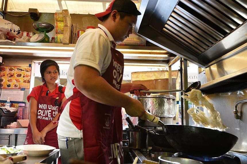 ITE student Sebastian Chua, 17, cooking sum lo hor fun at Hong Kong Street Old Chun Kee in Makansutra Gluttons Bay as his course mate Ilyzyana Kamis looks on. -- ST PHOTO: MARK CHEONG