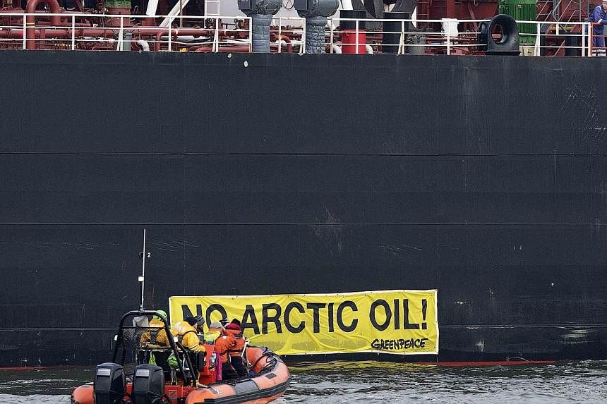 A crew member of the Russian oil tanker Mikhail Ulyanov looks on as members of Greenpeace sail past a banner saying "No Arctic Oil" on the vessel in the harbour of Rotterdam on May 1, 2014.&nbsp;Tens of degrees below zero during winter and home to en
