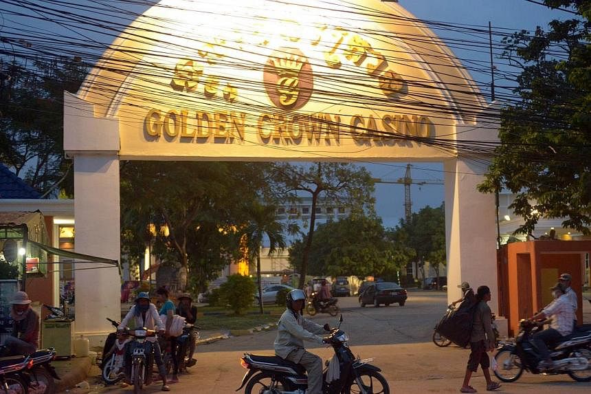 In a picture taken on June 19, 2014, a Cambodian man rides his motorbike past a gate of the Golden Crown Casino in the Thai-Cambodian border city of Poipet, northeastern Cambodian province of Banteay Meanchey. -- PHOTO: AFP&nbsp;