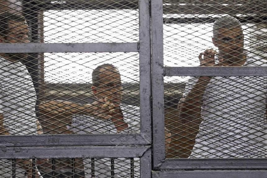 Al-Jazeera journalists (from left) Baher Mohamed, Peter Greste and Mohammed Fahmy behind bars in a court in Cairo earlier this month. The three were accused of aiding the blacklisted Muslim Brotherhood.&nbsp;PHOTO: REUTERS