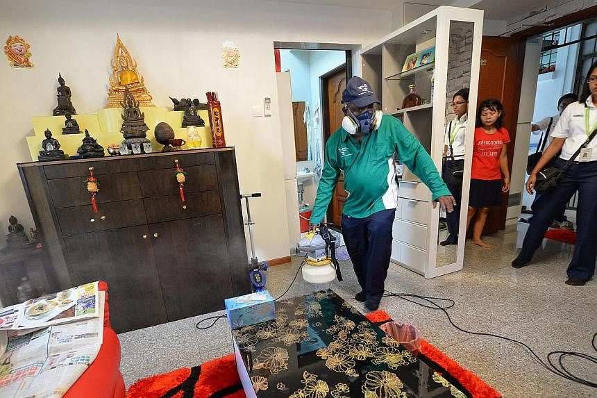 An environmental support assistant from the NEA spraying the living room of a private house along Simon Lane, in the Kovan area, with ultra-low-volume cold misting to fight dengue. The Government is paying particular attention to the area spanning Se