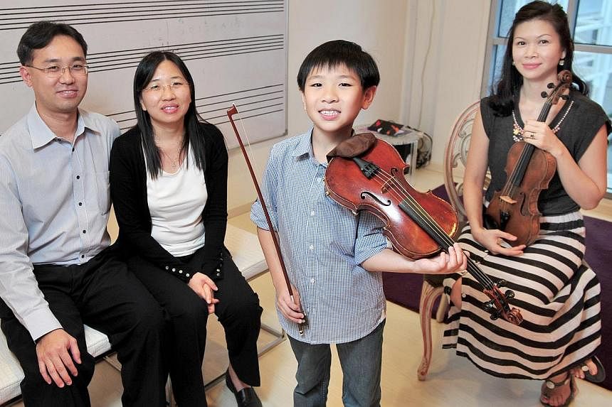 Young violinist Samuel Tan enjoys going for competitions because they offer him a chance to see other people playing the instrument. With him are his parents Jason Tan and Janis Low (both left) and his teacher Lee Huei Min.