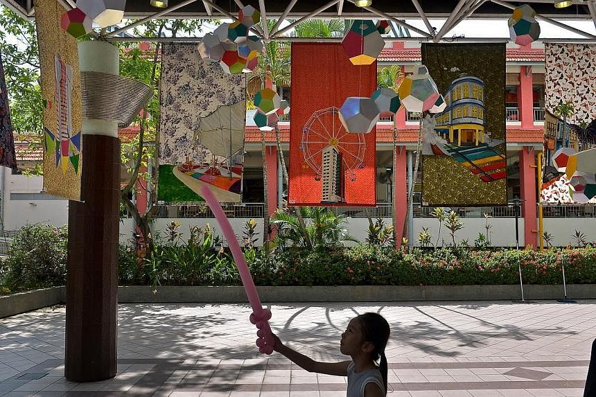 Peen Jin Xuan (centre), 6 , playing at the Colours of Carnival Installation which hang above him. -- ST PHOTO: KUA CHEE SIONG