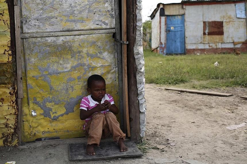 A child sits outside a locked shack in Nkaneng township, Marikana's informal settlement, in Rustenburg. -- PHOTO: REUTERS