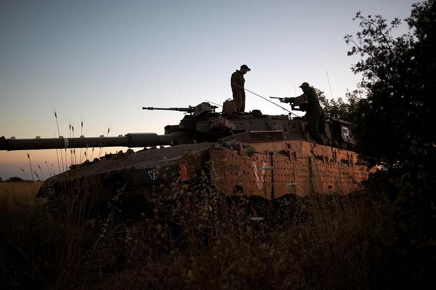Israeli soldiers are seen on their Merkava tank positioned near the Quneitra checkpoint on the border with Syria in the Israeli-annexed Golan Heights, on June 22, 2014. -- PHOTO: AFP