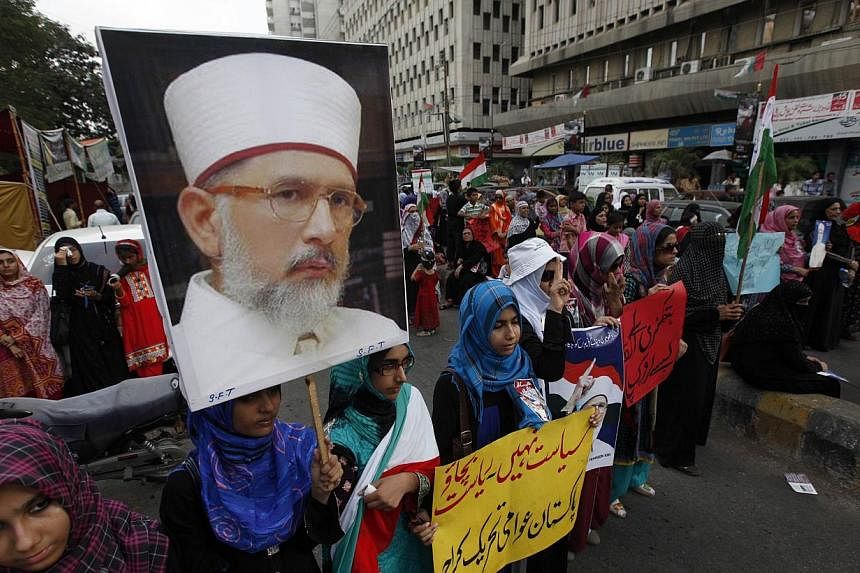 Female supporters of Tahirul Qadri, a Sufi cleric and the leader of the Awami Tehreek political party, hold his portrait during a protest in Karachi, condemning the deaths of their party's workers in Lahore on June 19, 2014. -- PHOTO: REUTERS&nbsp;