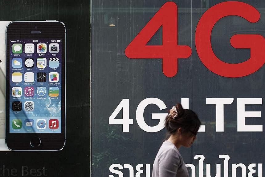 A woman walks past a billboard advertising 4G at a shopping district in Bangkok on June 20, 2014. Thailand's telecoms sector is fast emerging as the first economic casualty of an interventionist junta. -- PHOTO: REUTERS