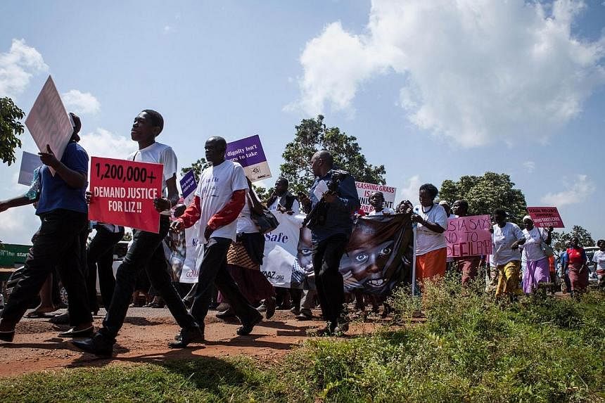 A protester holds a sign reading "1,200,000+ demand justice for Liz", as he takes part in a march through the Kenyan border town of Busia, on June 23, 2014,&nbsp;The trial of a man accused of carrying out a brutal gang rape of a schoolgirl, who was m