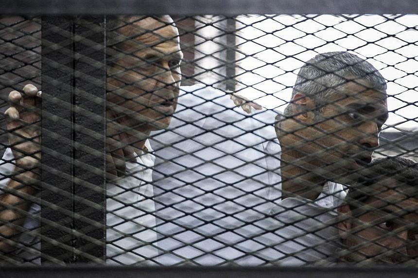 (From left) Al-Jazeera news channel's Australian journalist Peter Greste and his colleagues, Egyptian-Canadian Mohamed Fadel Fahmy and Egyptian Baher Mohamed, listen to the verdict inside the defendants cage during their trial for allegedly supportin