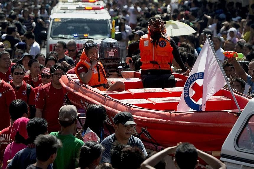 A roasted pig (centre right) dressed as a Red Cross rescue worker in a boat is paraded through the streets in Balayan, Batangas province, south of Manila on June 24, 2014, to celebrate the feast of St. John the Baptist. -- PHOTO: AFP