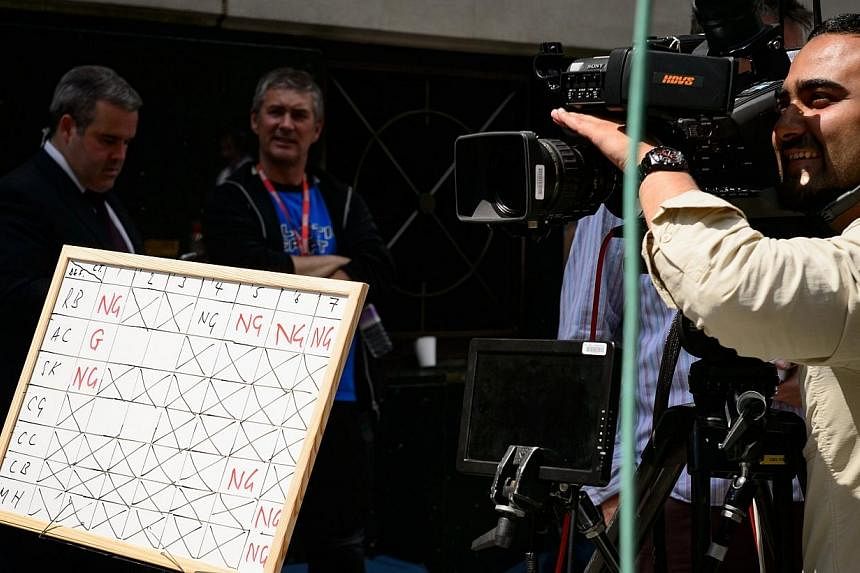 A television news crew keep track of the developments in the Phone-Hacking case using a dry marker board as verdicts begin to be returned, while they report from outside the Old Bailey in central London on June 24, 2014.&nbsp;British Prime Minister D