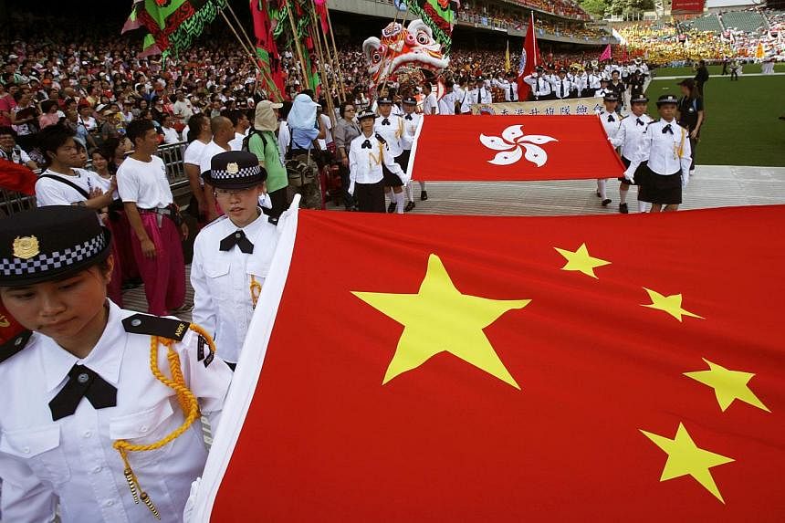Students carrying a national flag of China (front) and a Hong Kong flag during a parade at a Hong Kong stadium in 2009.