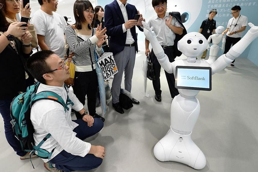 People look at humanoid robot 'Pepper', which is jointly developed by Japan's mobile carrier SoftBank and French humanoid robot maker Alderbaran, at a showroom of SoftBank in Tokyo on June 6, 2014. Softbank will release the robot next February with a