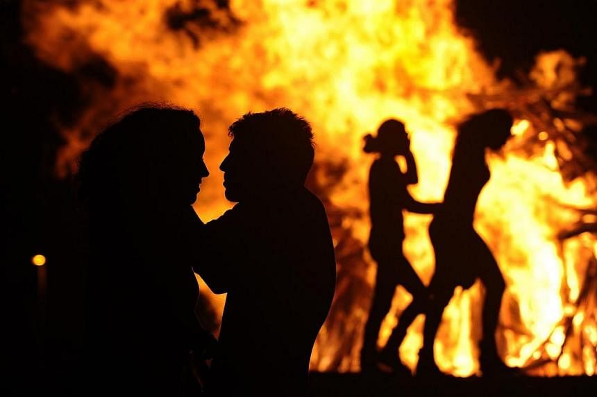 People attend a party held during the night of the San Juan bonfire on the beach of Playa de Poniente in Gijon early June 24, 2014. Fires formed by burning unwanted furniture, old schoolbooks, wood and effigies of malign spirits are seen across Spain