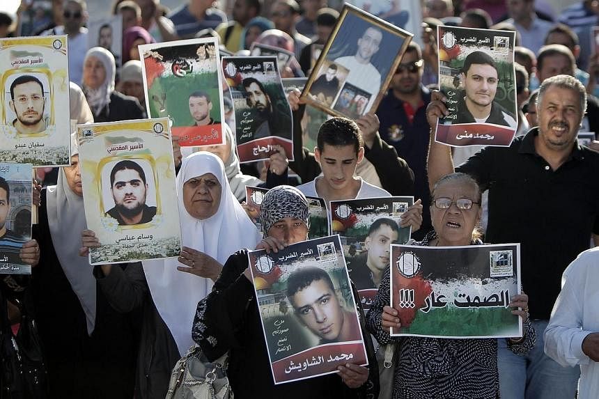 Palestinians hold posters with slogans and portraits of detainees during a demonstration on June 10, 2014, outside the Red Cross building in Jerusalem in support of Palestinian prisoners in Israeli jails who were on hunger strike.&nbsp;Sixty-three Pa