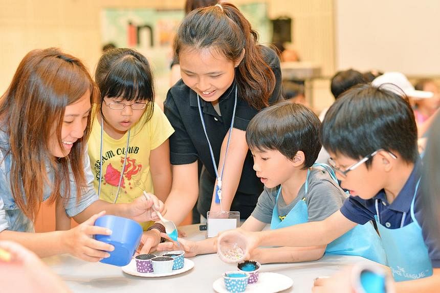 Young participants of the chemistry baking session included Chloe Ho (in yellow), seven, Talon Lee (in grey), six, and Dylan Ho (in blue), nine, seen here getting help to decorate their cupcakes.