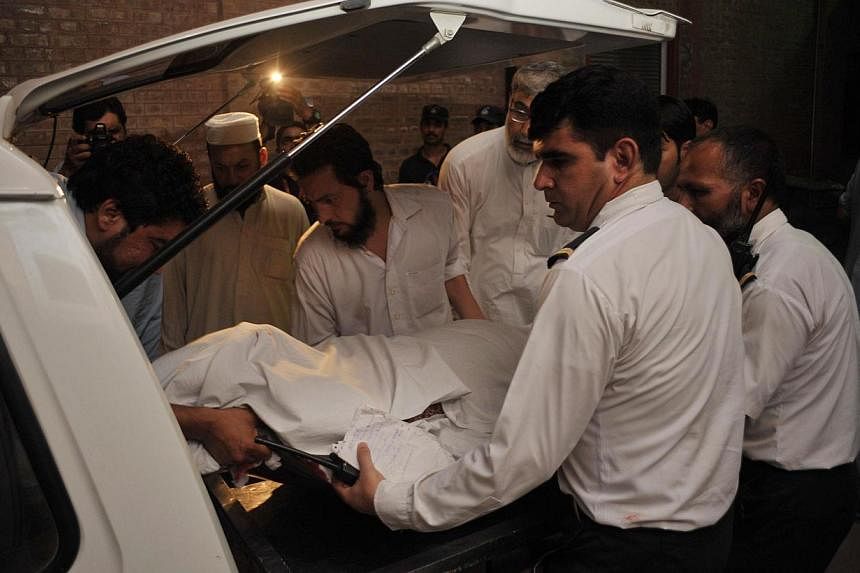 Pakistan International Airlines (PIA) officials move the dead body of a woman to an ambulance at the Bacha Khan International Airport in Peshawar on June 25, 2014, after an attack on a Pakistan International Airlines flight.&nbsp;Gunmen opened fire o