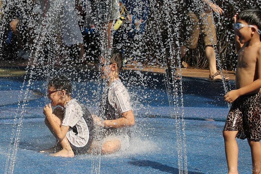 Children enjoying themselves at a water fountain to battle the hot weather. -- PHOTO: BERITA HARIAN FILE