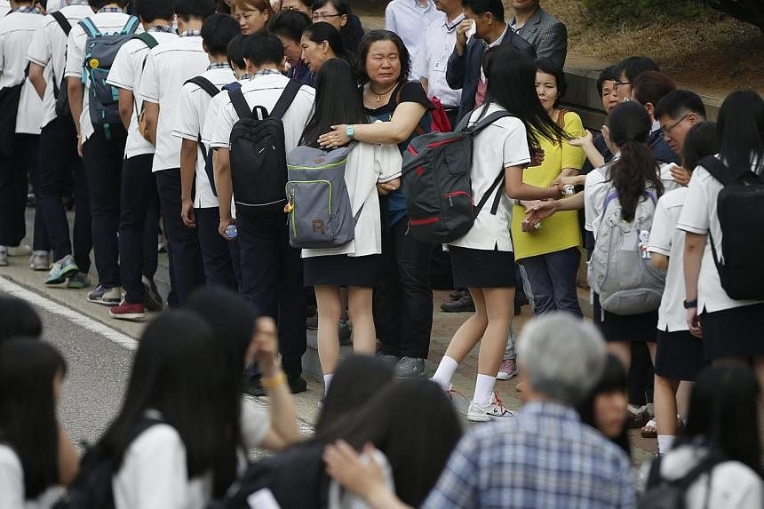 Relatives of the April 16 ferry disaster victims comfort students who survived the accident as they make their way back to school in Ansan June 25, 2014.&nbsp;The daughter of a crew member of a South Korean ferry which sank killing hundreds of school