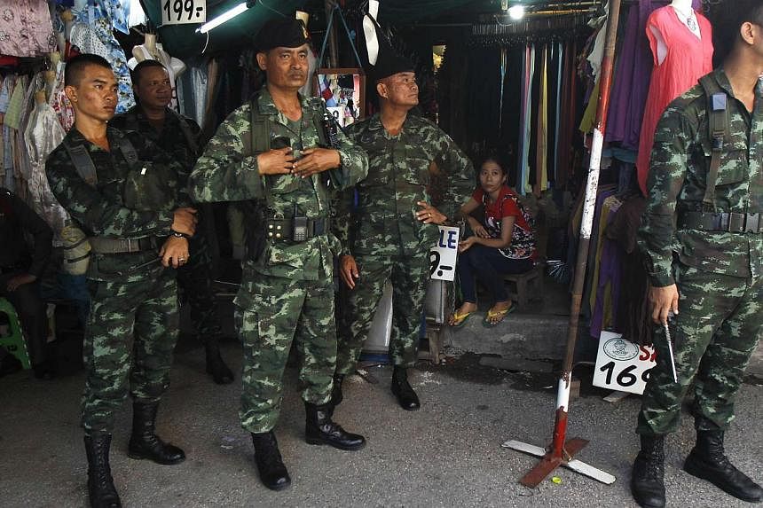 Soldiers stand guard at a shop at Chatuchak market in Bangkok on June 8, 2014. A senior Thai general has rejected reports that the army planned to rid the kingdom of the influence of controversial former premier Thaksin Shinawatra years before it sei