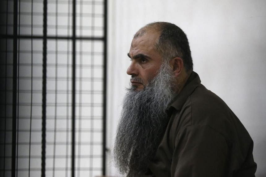 Radical Muslim cleric Abu Qatada looking on from behind bars at the State Security Court in Amman on June 26, 2014.&nbsp;The court acquitted him on Thursday regarding charges of conspiring to commit acts of terrorism. The cleric, who was extradited f