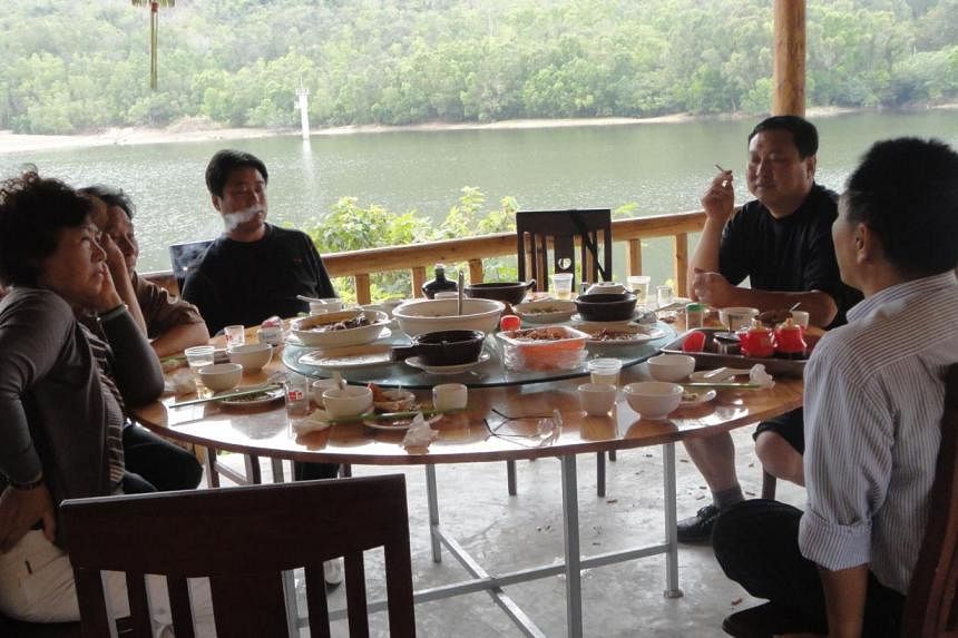 Activist Xu Xiangyu (left) and her husband (2nd left, partly obscured) at lunch in March 2011 with court and police officials who escorted her on a forced vacation to China's southern Hainan Island. Xu is one of dozens of campaigners who rights group