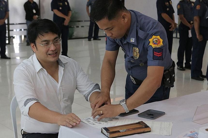 This handout photo released by the Philippine National Police (PNP) shows Philippine Senator Ramon Bong Revilla (centre) having his fingerprints taken at the PNP headquarters before he is brought to his detention cell on June 20, 2014. -- PHOTO: AFP 