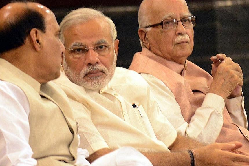Indian Prime Minister Narendra Modi (C) talks with Bharatiya Janata Party (BJP) President and Indian Minister of Home Affairs Rajnath Singh (L) as senior BJP leader Lal Krishna Advani looks on during the BJP parliamentary party meeting in New Delhi o