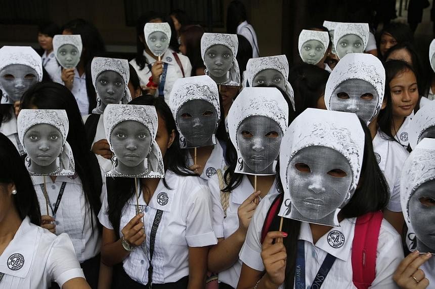 Students from an all-girls Catholic school, St Scholastica's College, wear masks depicting kidnapped African school girls in Manila, on June 27, 2014. -- PHOTO: REUTERS&nbsp;