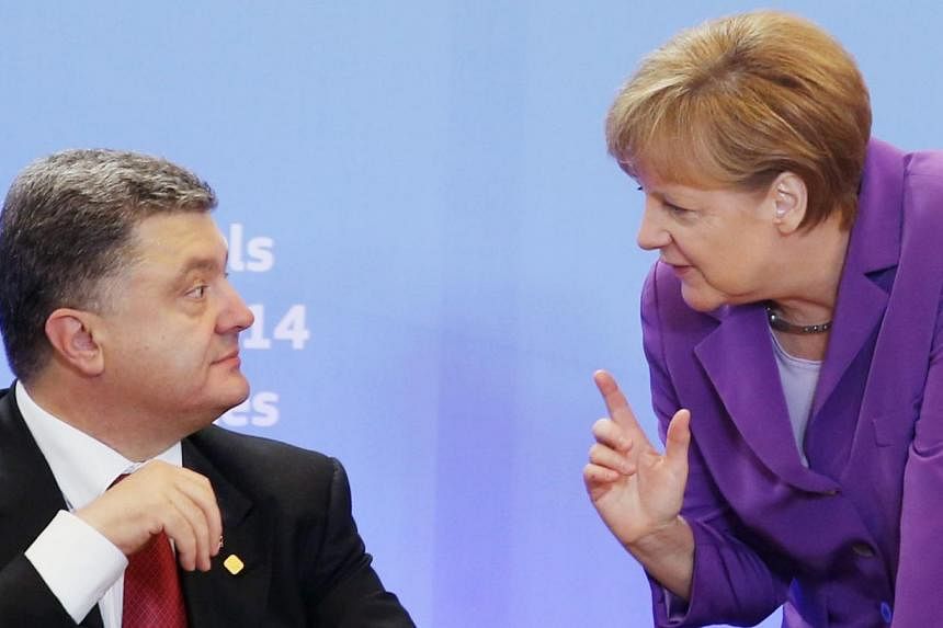 Ukraine's President Petro Poroshenko listening to Germany's Chancellor Angela Merkel during the cooperation agreement signing ceremony at the EU Council in Brussels on June 27, 2014. Ukraine signed a free-trade and political cooperation deal with the