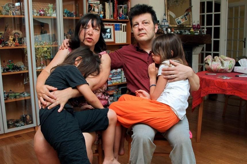 A photo taken on July 2, 2009, shows Sylvie and Dominique Mennesson, parents of twins born in 2000 from a surrogate mother from California, as they pose with their daughters at their home in Maison Alfort, France. They turned to the&nbsp;European Cou