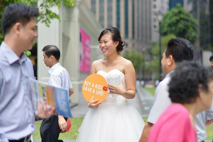 Ms Kwa Mee Ling, 20, a Singapore Management University student, was one of the "brides" at Raffles Place yesterday asking people for cash donations for the Bone Marrow Donor Programme or to sign up as donors. Those who made donations were given a Her