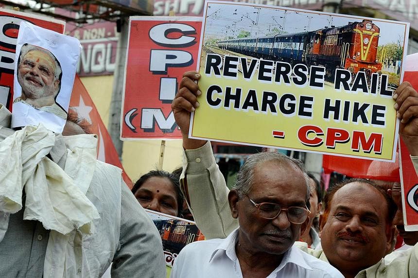Indian activists of the Communist Party of India-Marxists (CPI-M) holding placards and an effigy representing Prime Minister Narendra Modi during their protest against the price hike in railway fares, in Hyderabad on June 21, 2014. -- FILE PHOTO: AFP