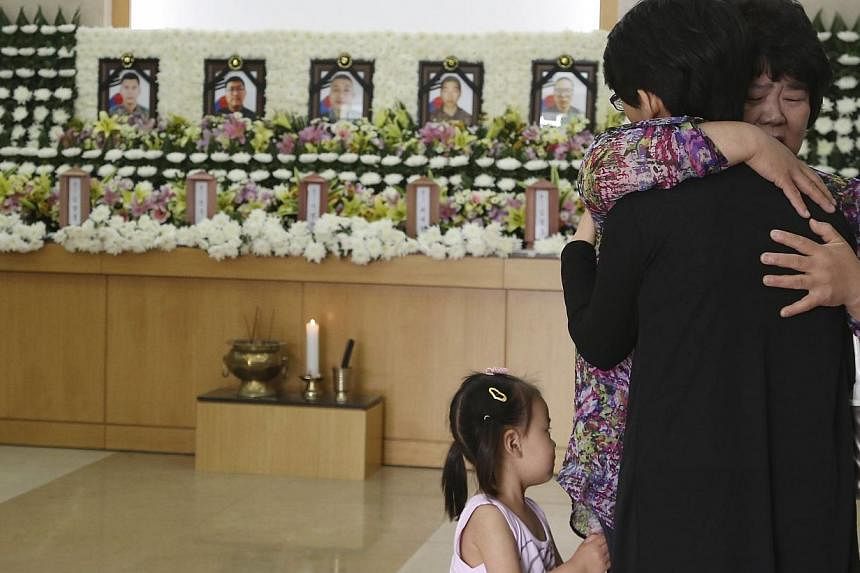A mourner comforts a relative of a dead soldier on June 23, 2014&nbsp;after paying her tribute at the group memorial altar of the five soldiers who were killed by a conscript soldier, identified as Sergeant Lim. -- PHOTO: REUTERS