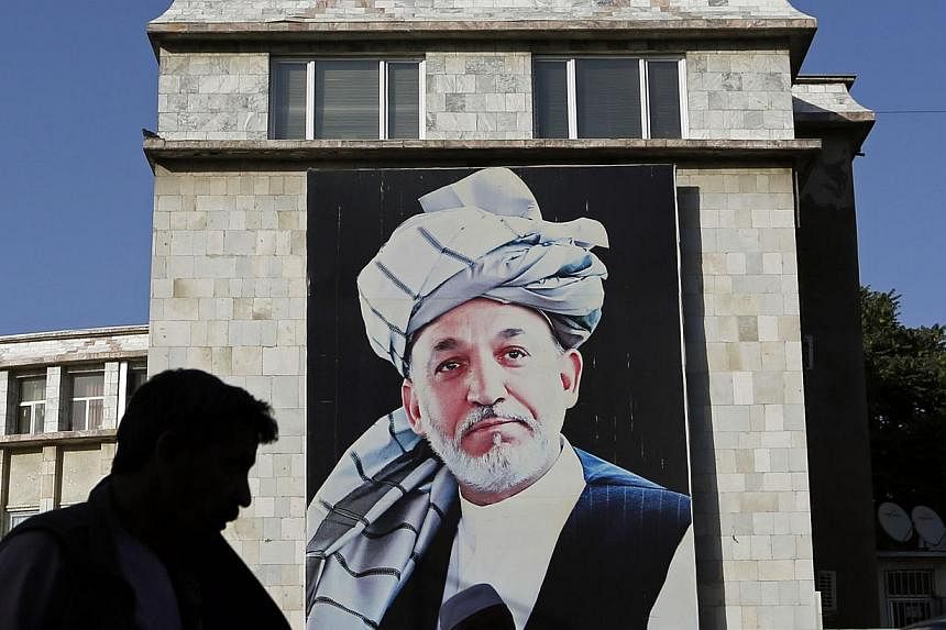 People walk past a picture of Afghan President Hamid Karzai on a street in Kabul on June 26, 2014.&nbsp;The Afghan president may not have signed a key measure aimed at clamping down on the financing of terrorism, reviving concern the country's banks 